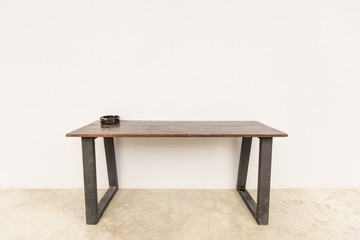 Black Ashtray with cigarette butt on the table by the wall.