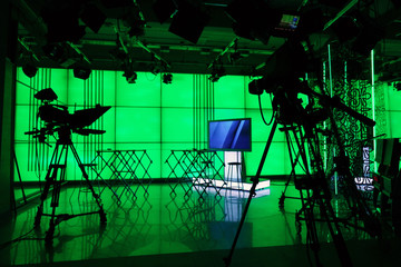 Silhouette of a digital video camera in front of a green screen.