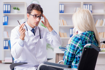 Obraz premium Disabled woman in wheel chair visiting man doctor