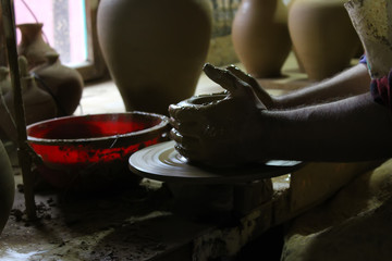 A raw clay pot in the hands of a Potter. Pottery art work:Hands make the mold with spirituality. Craftsman artist making craft, pottery, sculptor from fresh wet clay on pottery wheel, selected focus