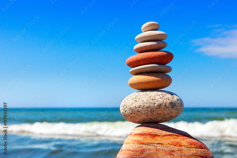 Wall mural Pyramid of multicolored pebbles on a background of the summer sea.