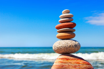 Pyramid of multicolored pebbles on a background of the summer sea.