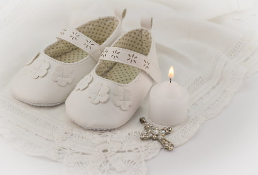 Christening booties invitation background with white lace, candle and crystal cross pendant