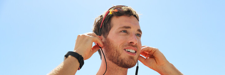 Young man putting in ear wireless bluetooth earphones wearing wearable technology. Happy person...