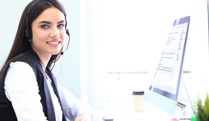 Businesswoman wearing microphone headset using computer in the office - operator, call center.