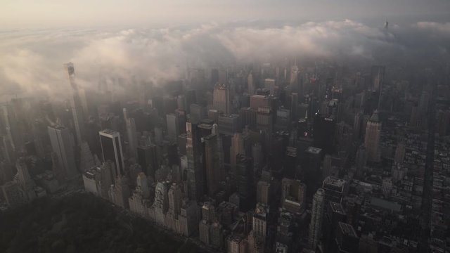 New York City aerial view of Midtown Manhattan skyscrapers from Central Park, at sunrise, under fog and low level clouds.