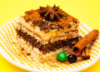delicious portion of tiramisu with candies and cinnamon on yellow background
