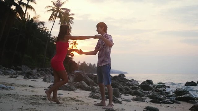 Young pretty couple dancing a slow dance on tropical beach at sunset time. slow motion. 1920x1080