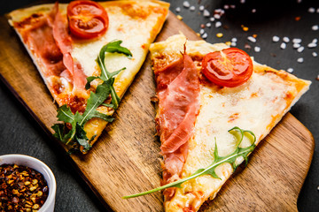 Slices of pizza with ham and vegetables on wooden table