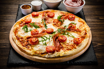 Pizza with ham and vegetables on wooden table
