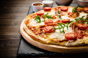 Pizza with ham and vegetables on wooden table