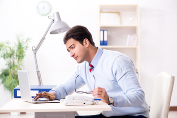 Young handsome businessman employee working in office at desk