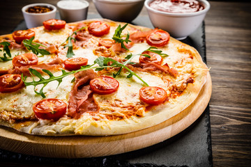 Pizza with ham and vegetables on wooden table