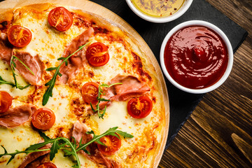 Pizza with ham and vegetables on wooden table