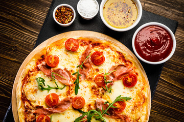 Pizza with ham and vegetables on wooden table