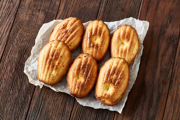Sweet almond cookies put in rows on white paper over wooden background, close-up, selective focus