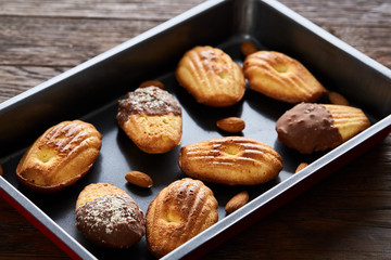 Freshly baked almond cookies on cooking tray over wooden background, top view, selective focus.