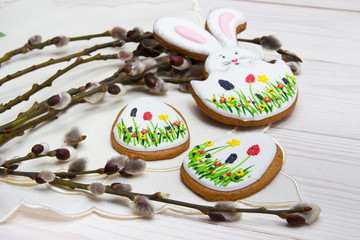 Easter gingerbread set and willow twig on white wooden background.  Easter Bunny and eggs, gingerbread