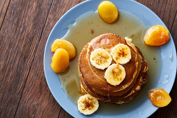 Pile of homemade pancakes with honey and walnuts on rustic wooden background, selective focus