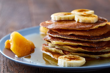 Pile of homemade pancakes with honey and walnuts on rustic wooden background, selective focus
