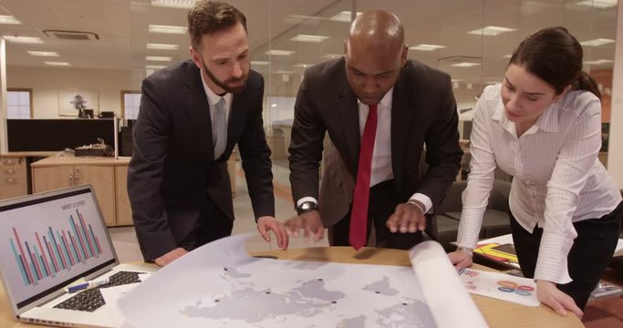 Business partners discussing & brainstorming ideas at a meeting with a world map
