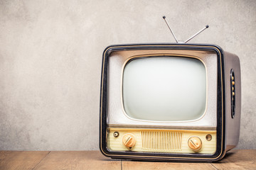 Retro old TV set receiver on table front textured concrete wall background. Broadcasting concept. Vintage style filtered photo