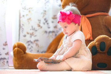 Fototapeta premium 10 months old baby girl examining a book