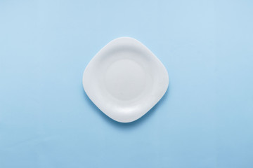 Single empty plate on pastel blue background top view flat lay