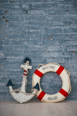 Composition on a sea theme with an anchor and life ring on a gray brick wall.