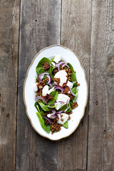 Salad with lenses and spinach on wooden background