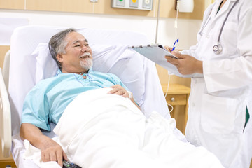 Old patient lying in hospital bed. Doctor holding clipboard and taking to him.