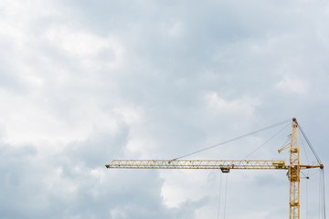 A construction yellow crane against the background of a dark sky.