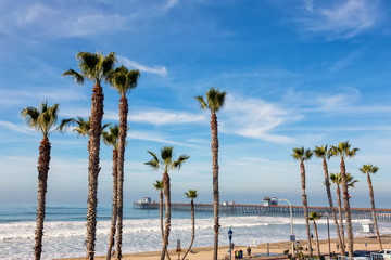 California Oceanside pier over the ocean with palm trees and beach, travel destination - 197843469