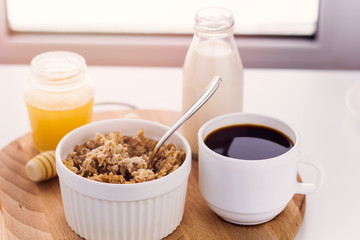 healthy breakfast fresh cereal, milk bottle, coffee cup and honey jar sunny warm toned