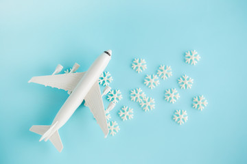 Fototapeta premium Plastic toy airplane and white snowflakes on Blue sky Background.