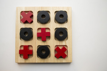 Wooden tic tac toe game on white background. Red crosses and black noughts