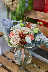 a bouquet of flowers in a glass vase on a background of wooden boards in a warm brown scale.