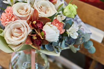 a bouquet of flowers in a glass vase on a background of wooden boards in a warm brown scale.