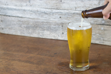 cold beer in bottle fill to glass on wood table