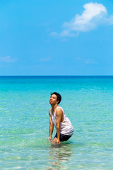 Fototapeta na wymiar The man is fun and enjoy swimmimg or playing in the clear sea and blue sky background inthe sunny day ,Thailand.