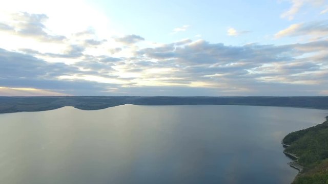 Great sunset on the lake between the mountains. A couple hugging at the edge of the cliff. 4k