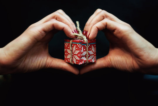 Close up view of a little present in woman's hends in the heart form