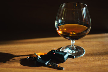 Cognac glass with alcohol on the table with car keys