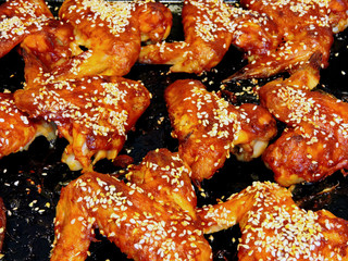 Ruddy baked wings with sesame seeds. Baked chicken wings on a baking sheet. Barbecue chicken wings.