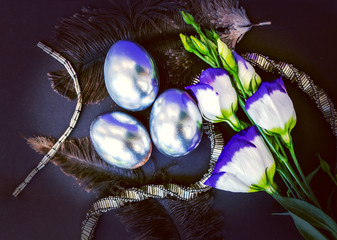 Silver eggs with Prairie Gentian and beaded silver necklace on a dark background, Easter