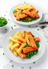 British Traditional Fish finger and chips with peas and tartar sauce in a white plate.