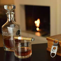 liqueur and cigar in the foreground on table and lit fireplace in the background