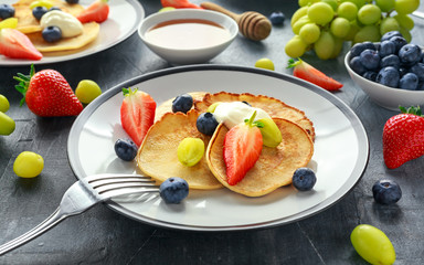 Homemade Pancakes with Blueberry, Strawberry, green Grape and honey syrup. served on plate