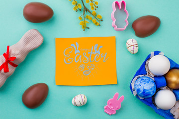 Happy Easter card and decorations. Chocolate bunny, eggs and silicone rabbit shape molds on colorful background. Spring and Easter concept.
