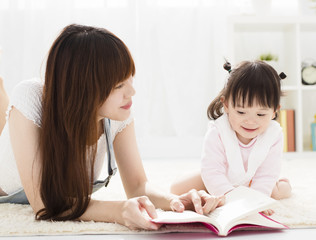 happy Mother reading book to daughter.